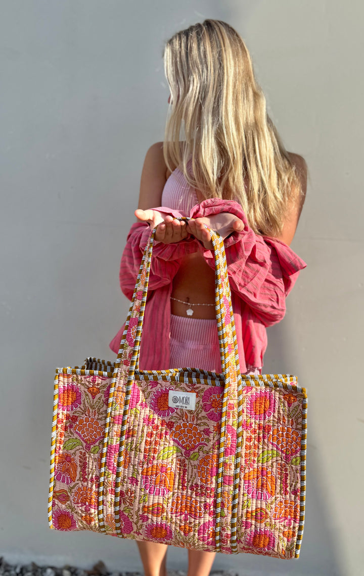 Woman holding a colorful patterned bag against a plain background
