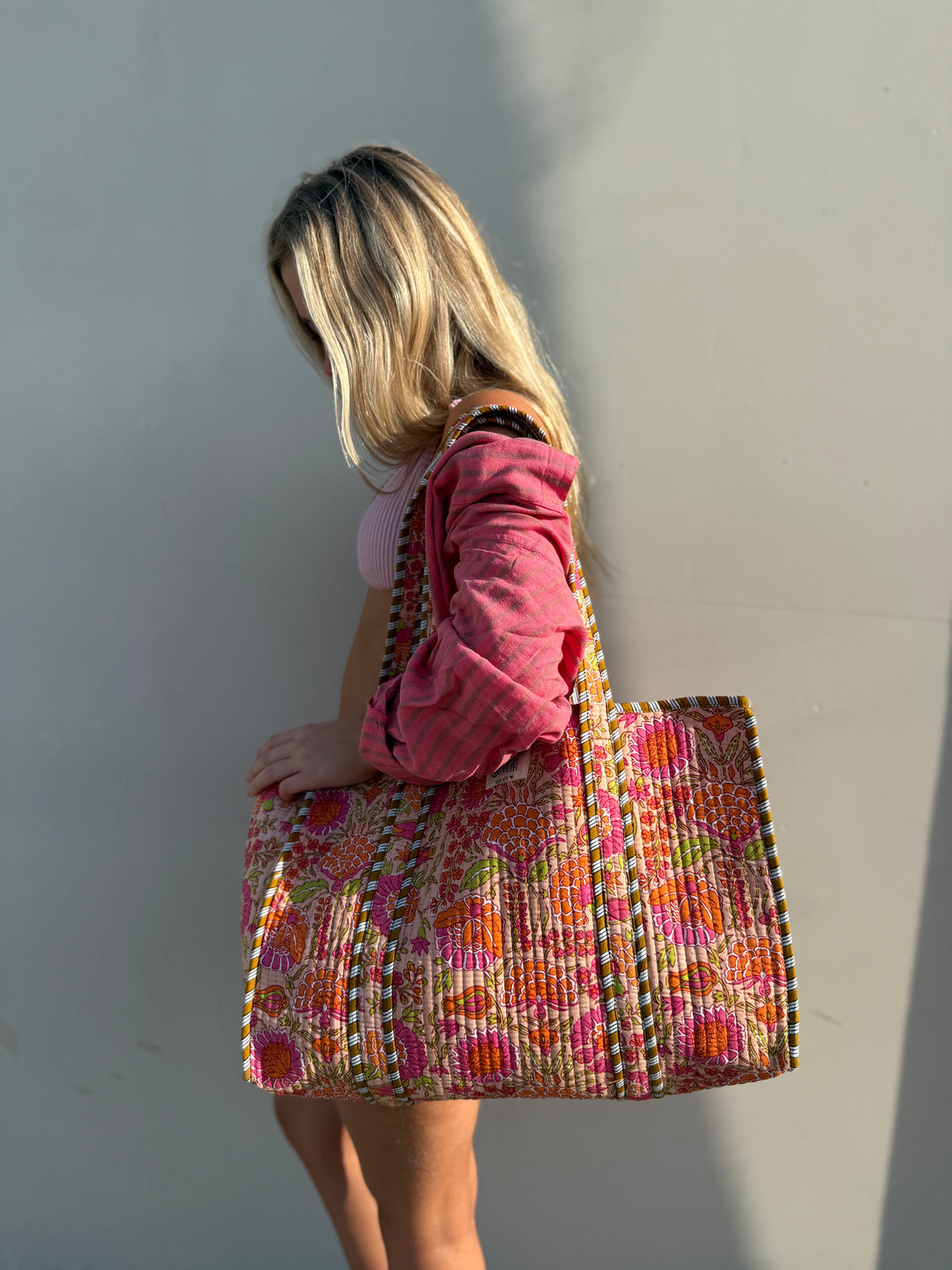 Person holding a colorful woven bag against a plain background