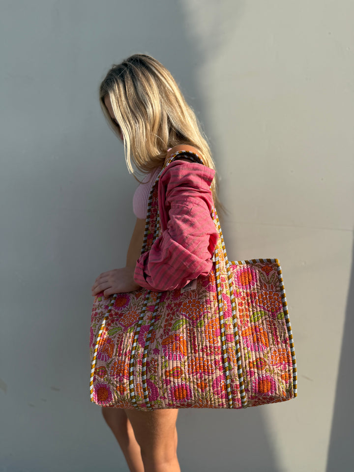 Person holding a colorful woven bag against a plain background