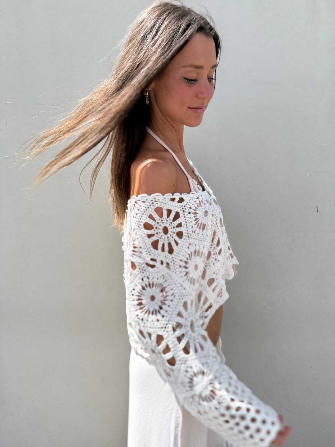 Woman wearing a white crochet cover-up against a plain background