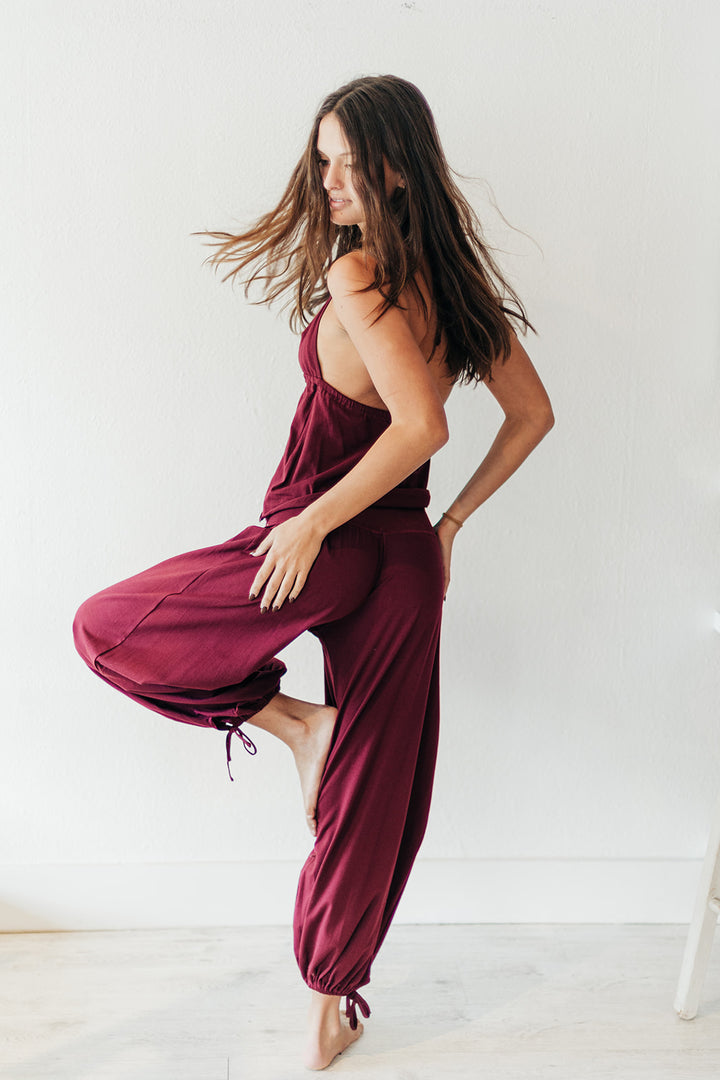 Woman wearing a burgundy jumpsuit against a white background