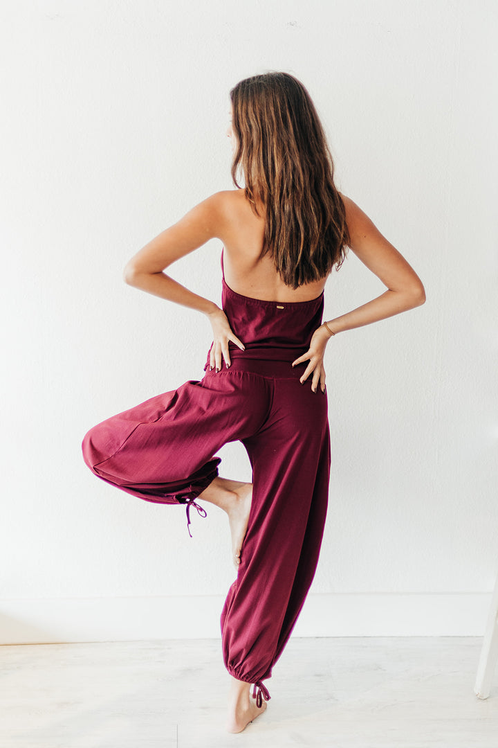 Woman wearing a burgundy jumpsuit against a white background
