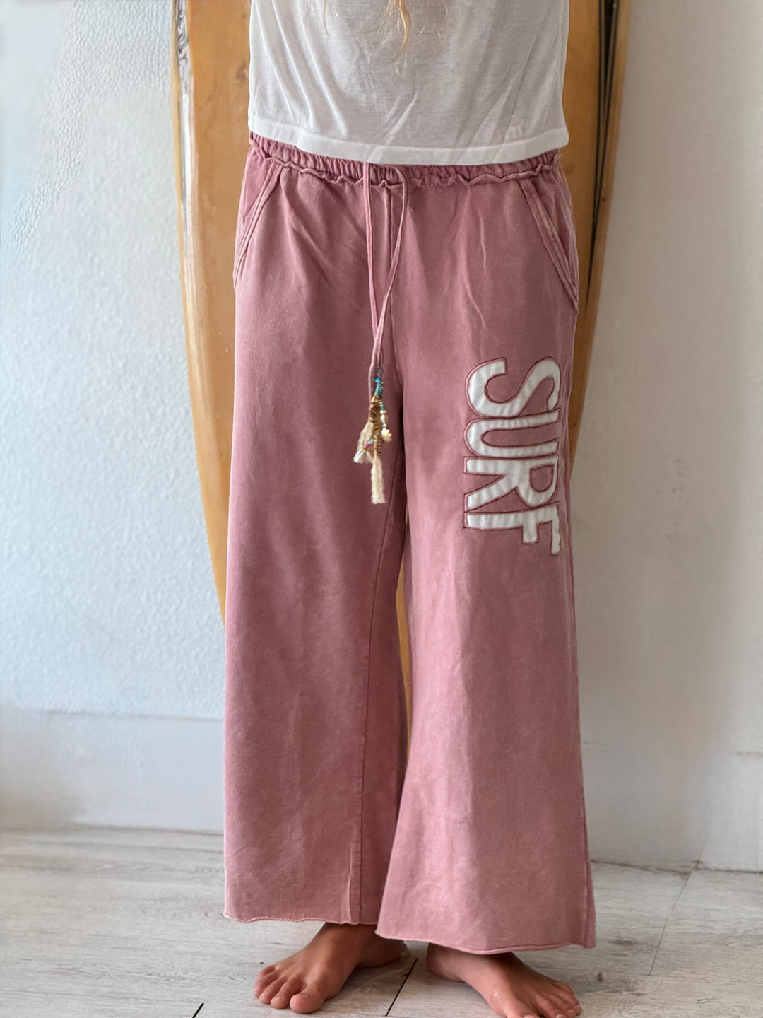 A person wearing dusty rose wide-leg lounge pants with a white &