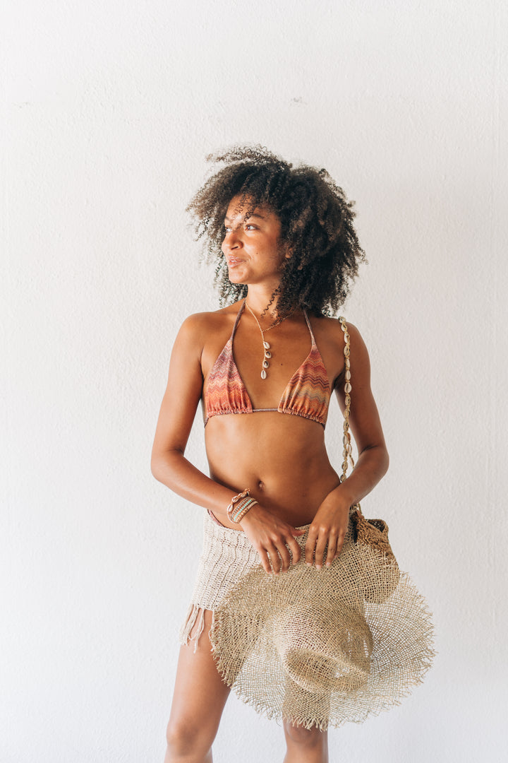 Woman wearing a bikini and holding a bag against a white background