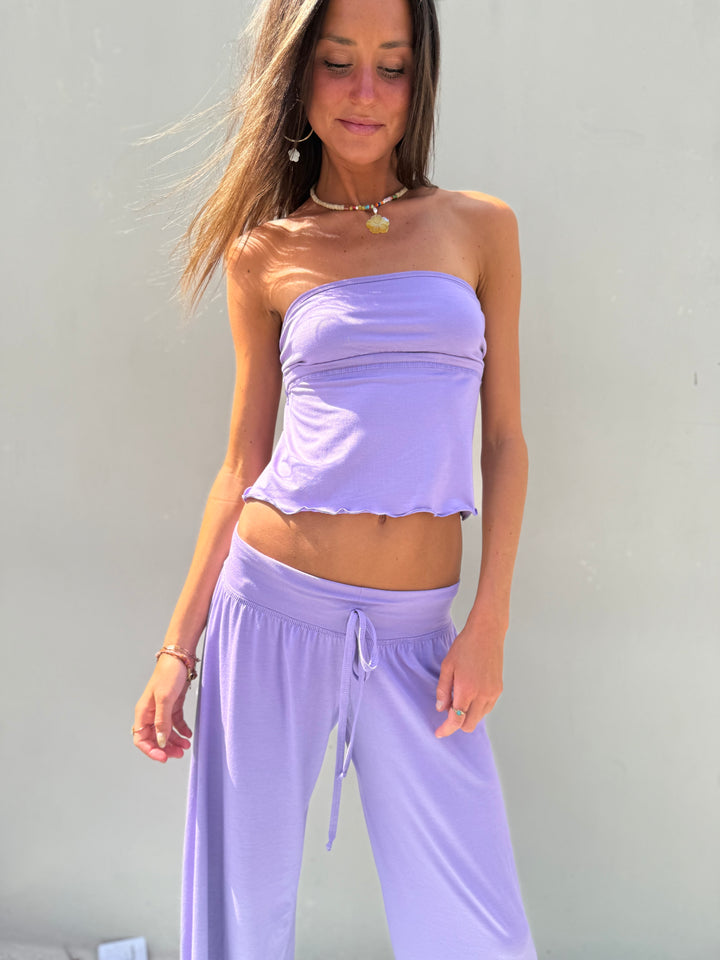 Woman wearing a matching lavender top and pants against a plain background