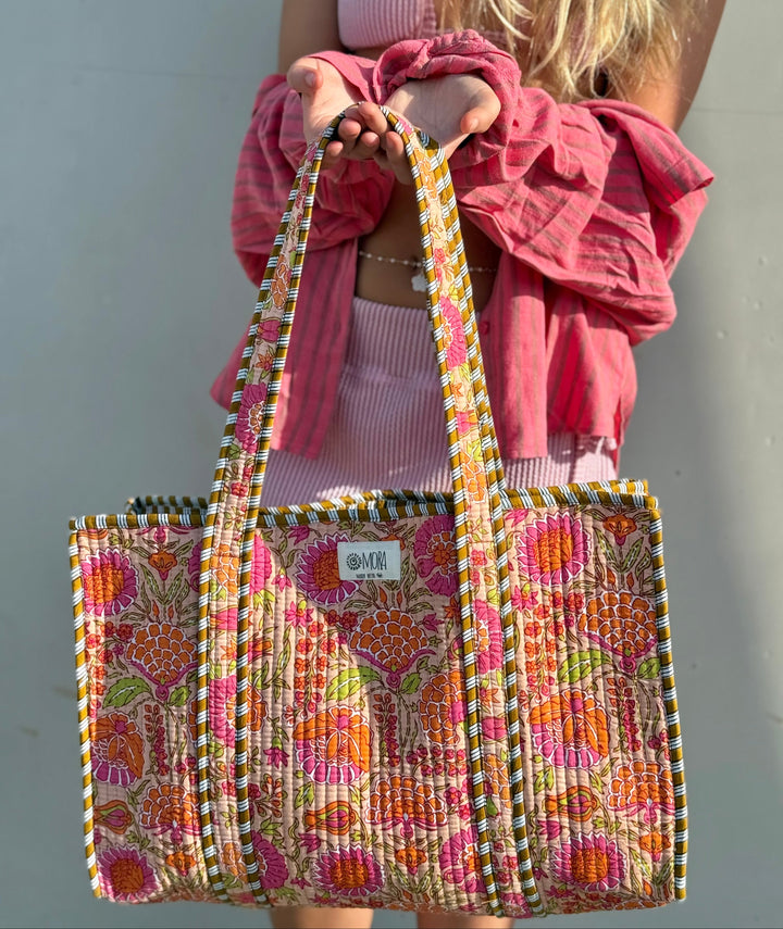 Person holding a colorful patterned tote bag against a plain background