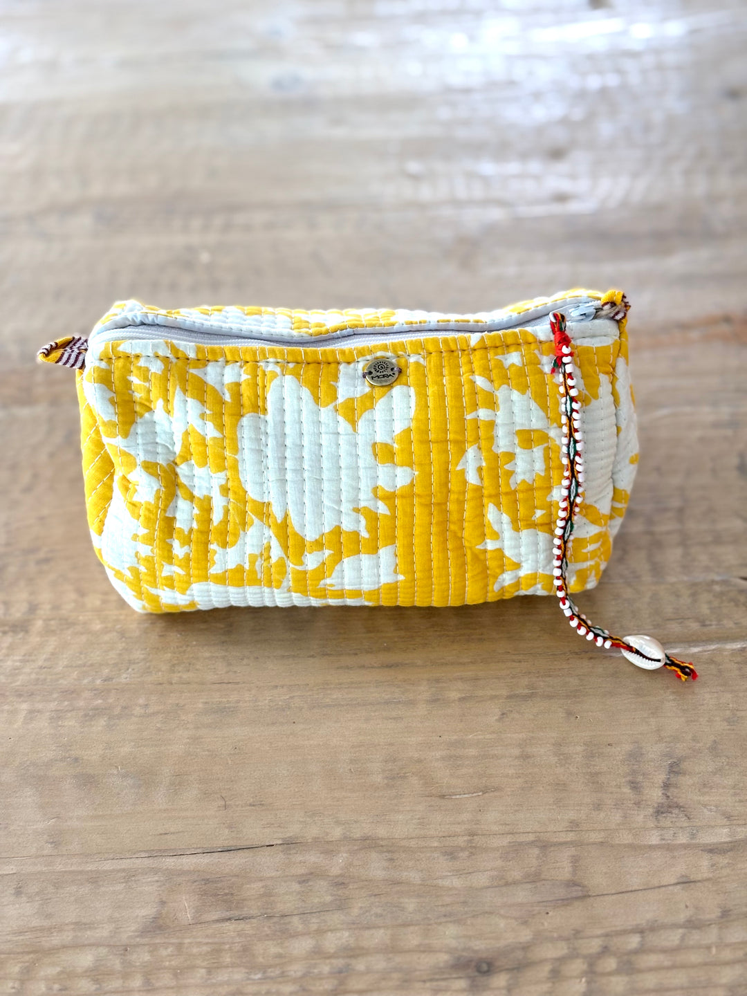 Yellow and white floral patterned pouch on a wooden surface