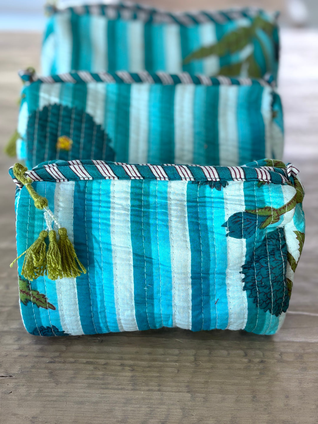 Set of blue and white striped fabric bags with floral patterns on a wooden surface