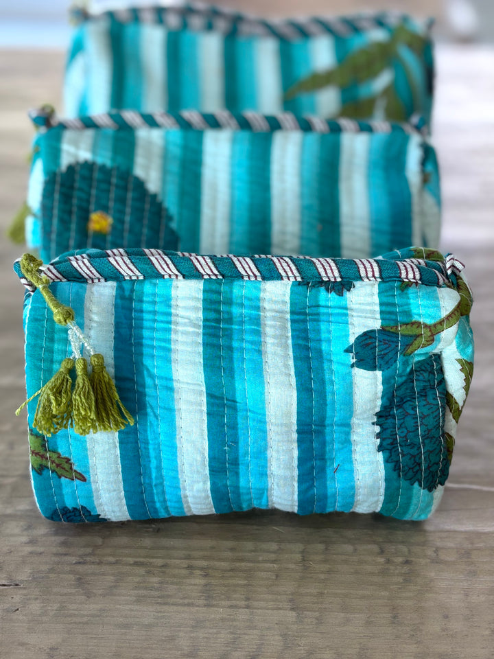 Set of blue and white striped fabric bags with floral patterns on a wooden surface