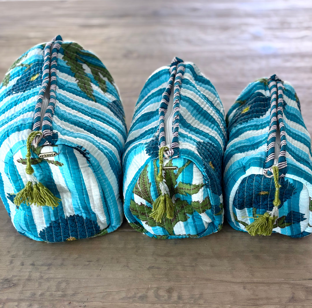 Three blue and white striped bags with tassels on a wooden surface