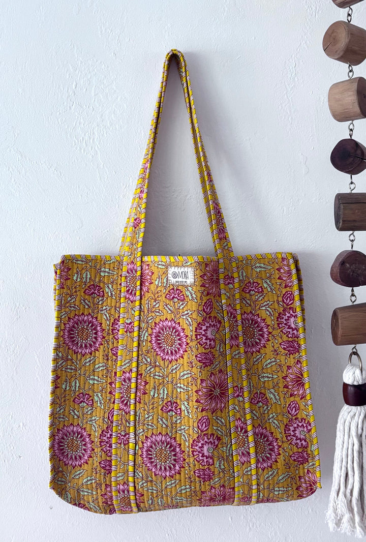 Floral patterned tote bag hanging on a white wall with decorative elements.