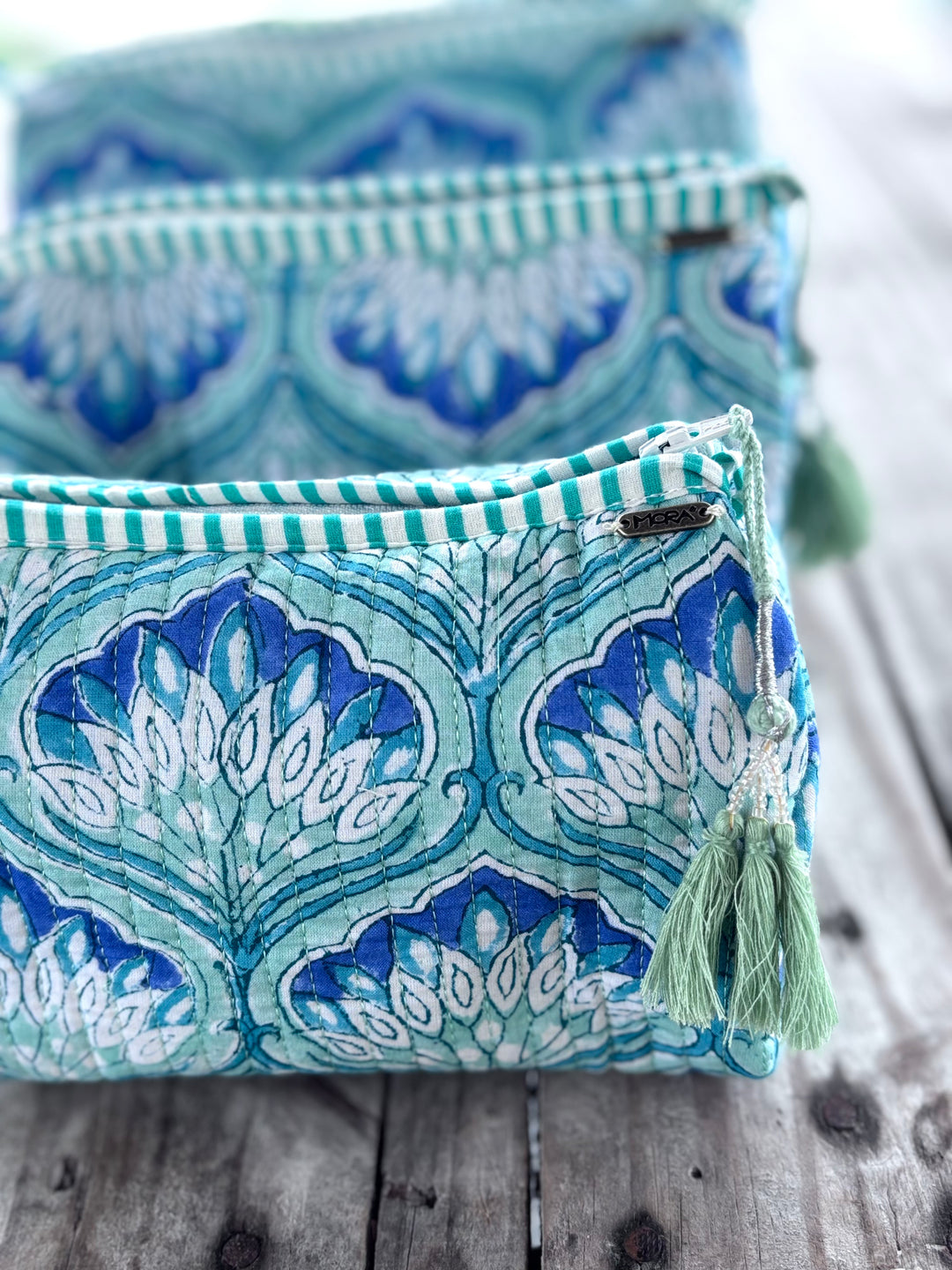 Green patterned fabric draped over a stand against a white wall.