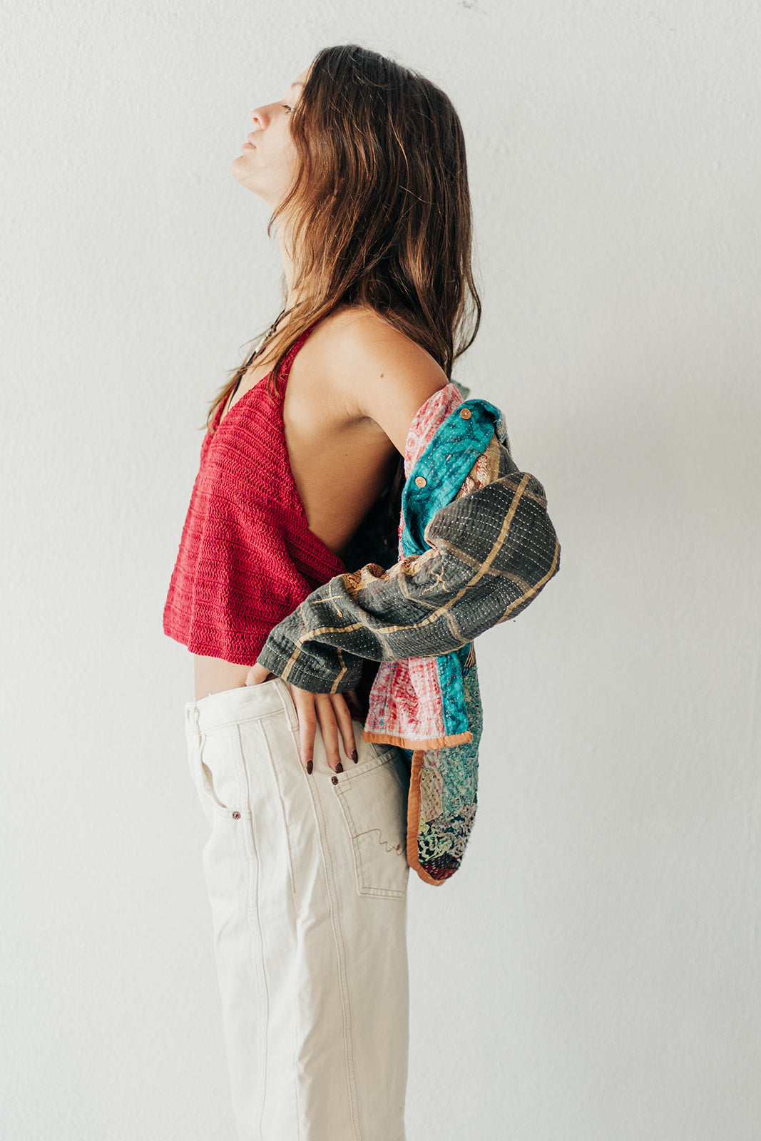 Woman holding a colorful jacket against a plain background