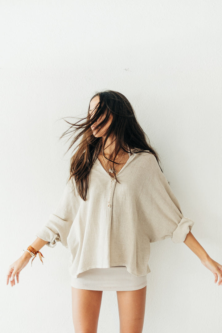 Woman wearing a beige oversized shirt against a white background