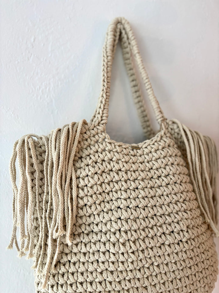 Beige crochet bag with tassels on a white background