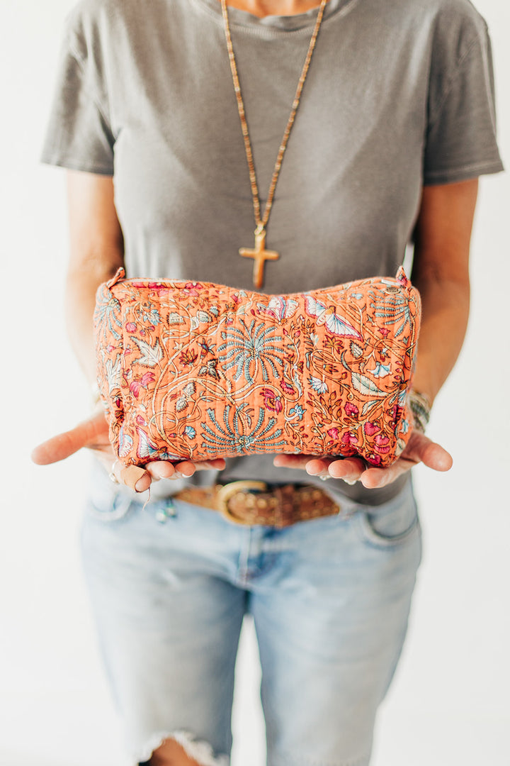 Person holding a colorful embroidered clutch with a neutral background