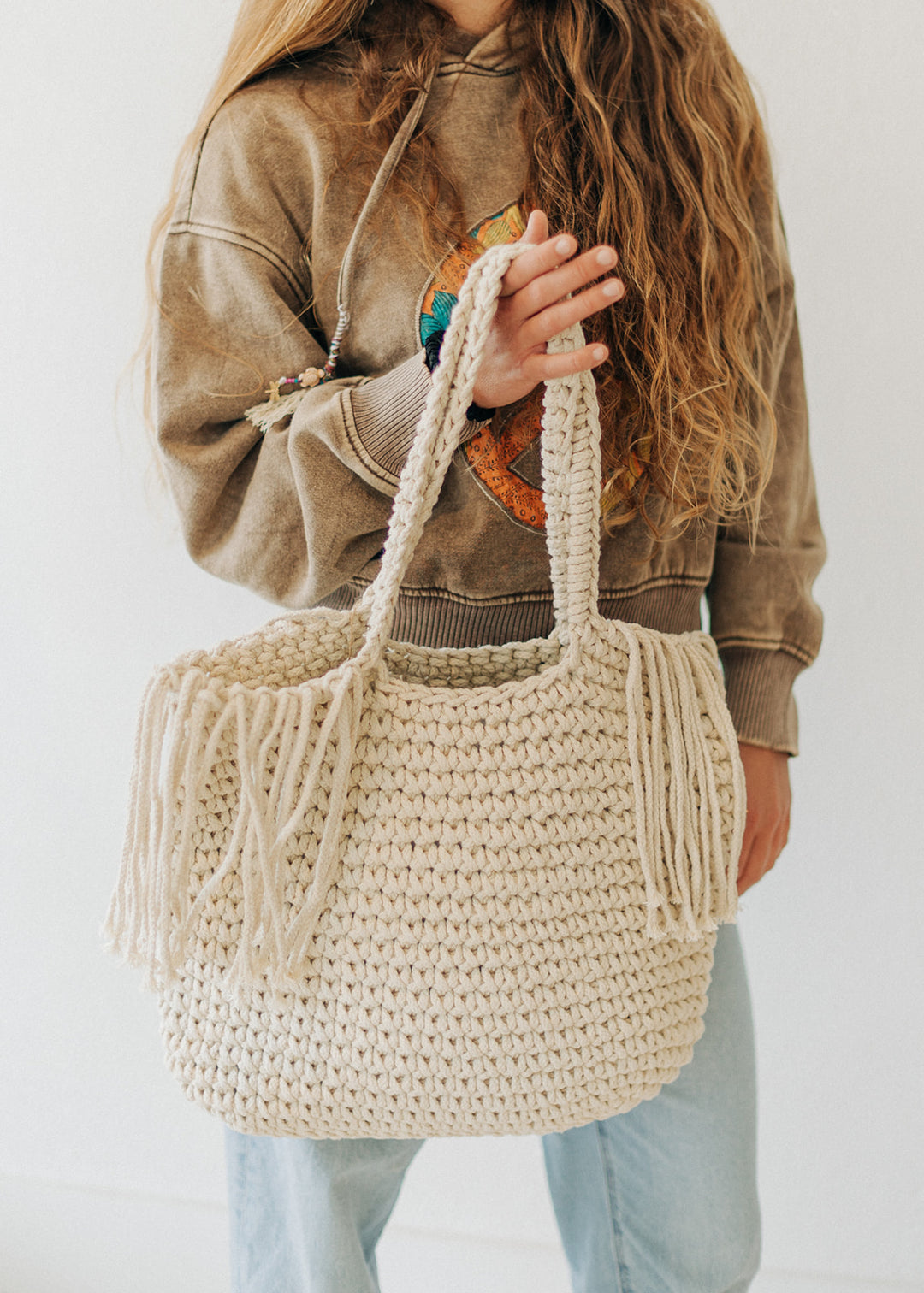 Person holding a woven beige handbag against a plain background