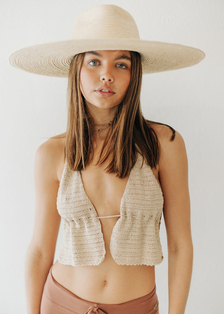 Woman wearing a straw hat and crochet top against a white background