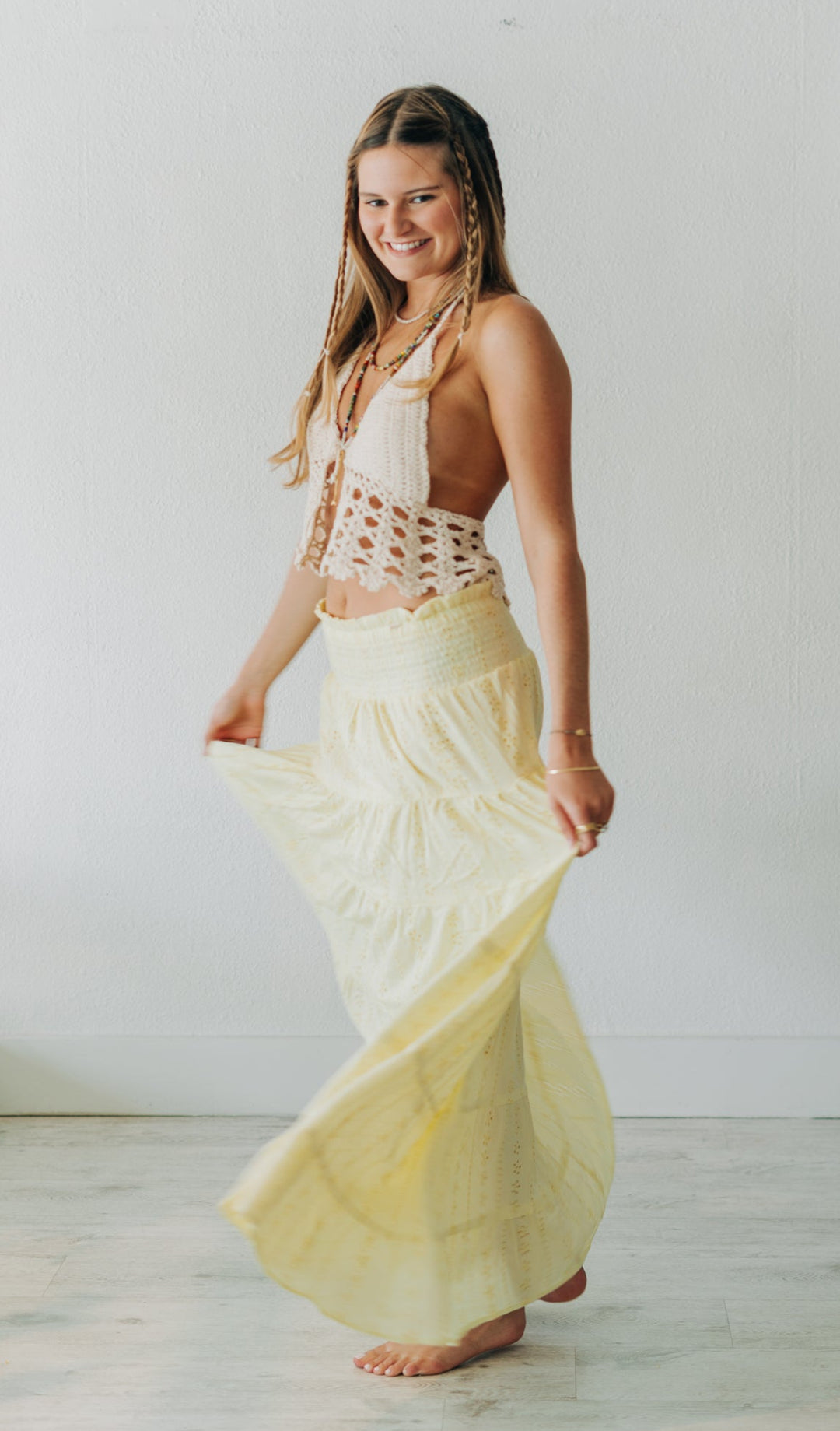 Woman wearing a white top and yellow skirt in a minimalistic room.