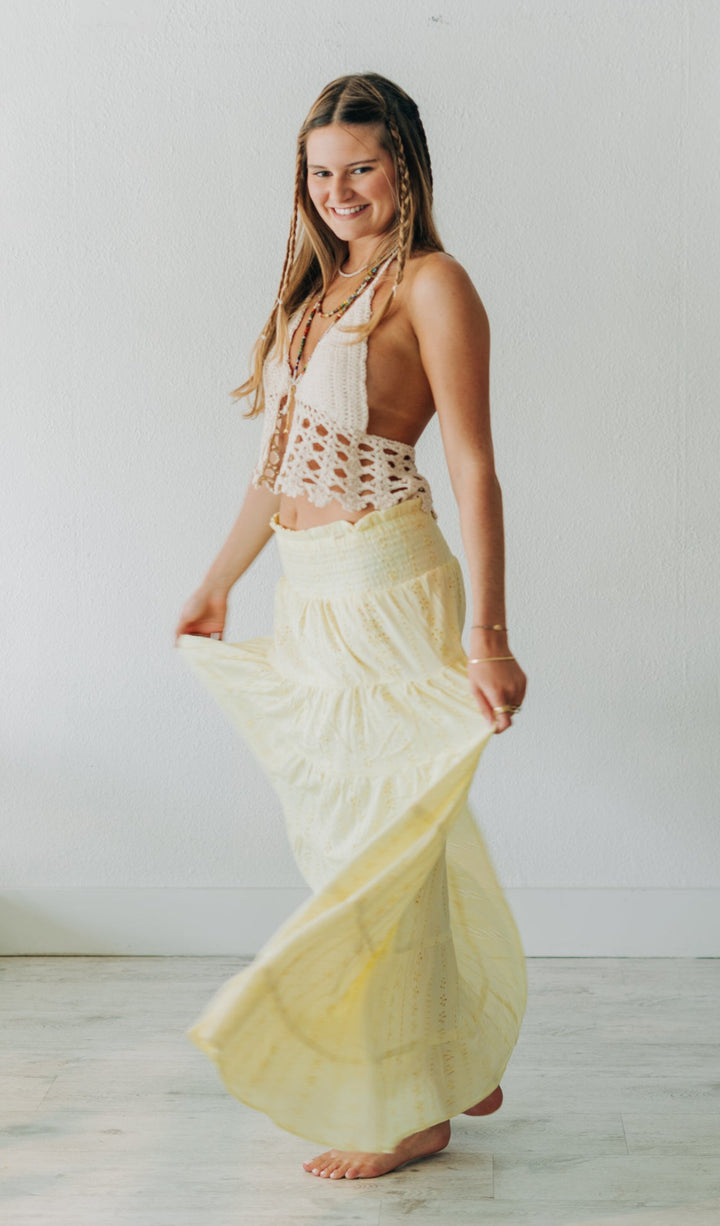 Woman wearing a white top and yellow skirt in a minimalistic room.