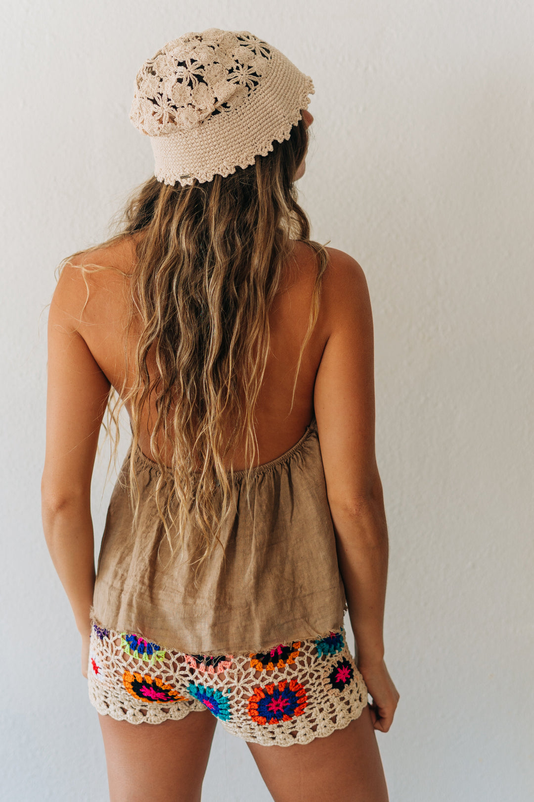 Person wearing a beige sleeveless top and colorful crochet shorts with a white background