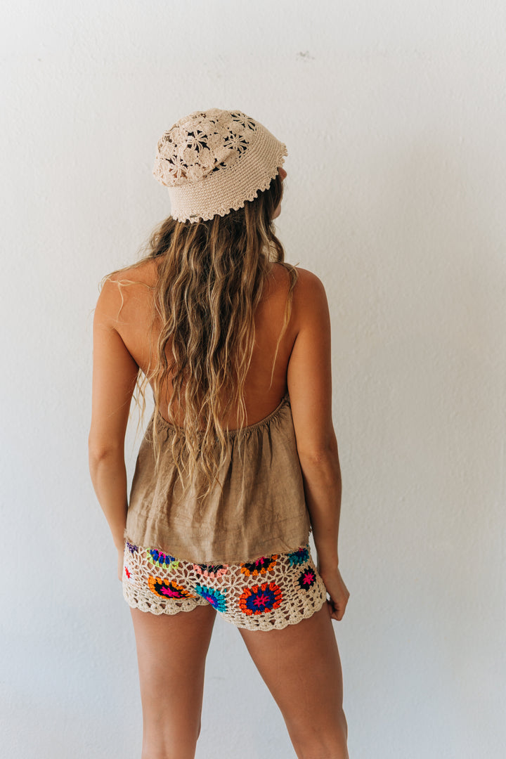 Person wearing a beige sleeveless top and colorful crochet shorts with a white background
