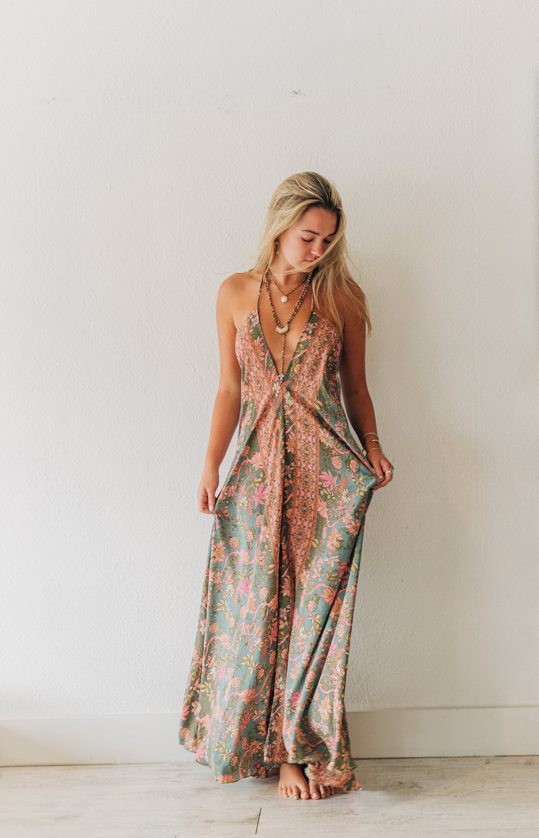 Woman wearing a floral dress standing against a white wall.