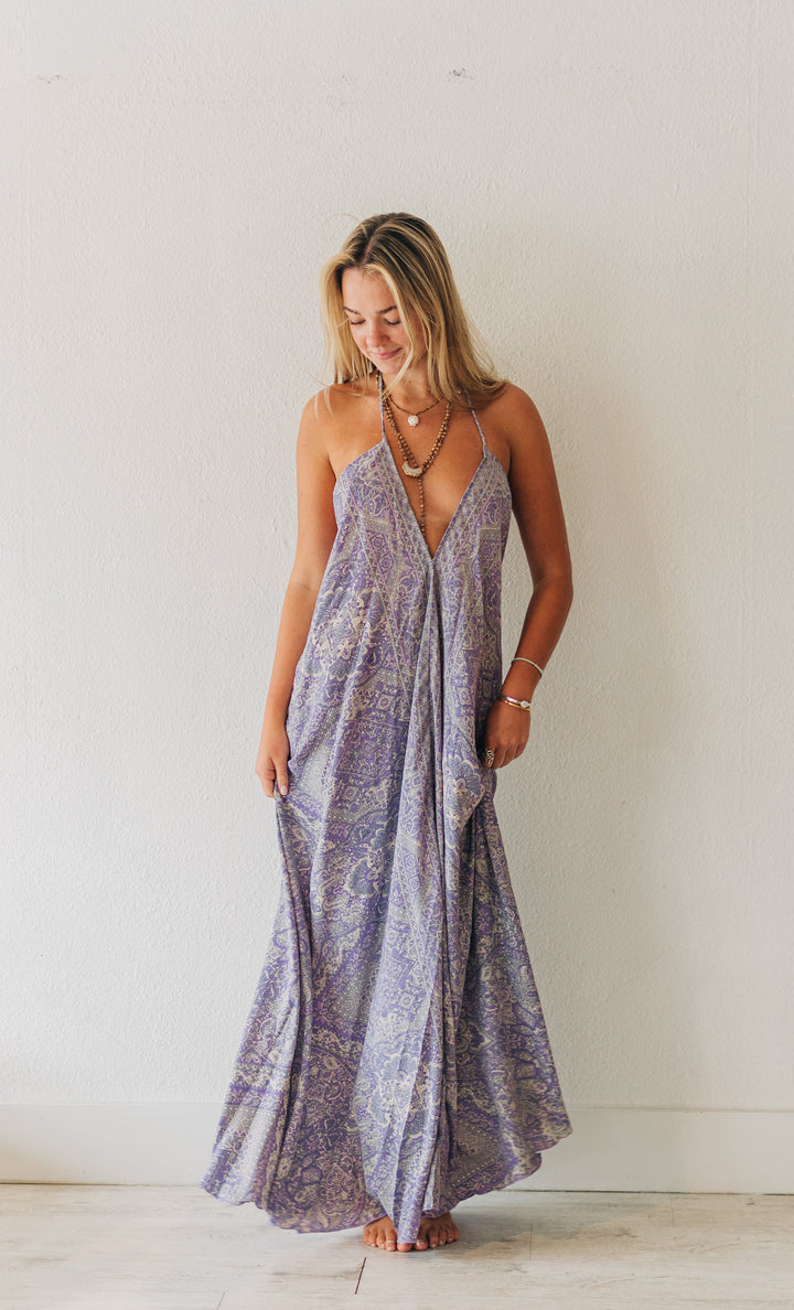 Woman in a long, patterned dress standing in a minimalistic room.