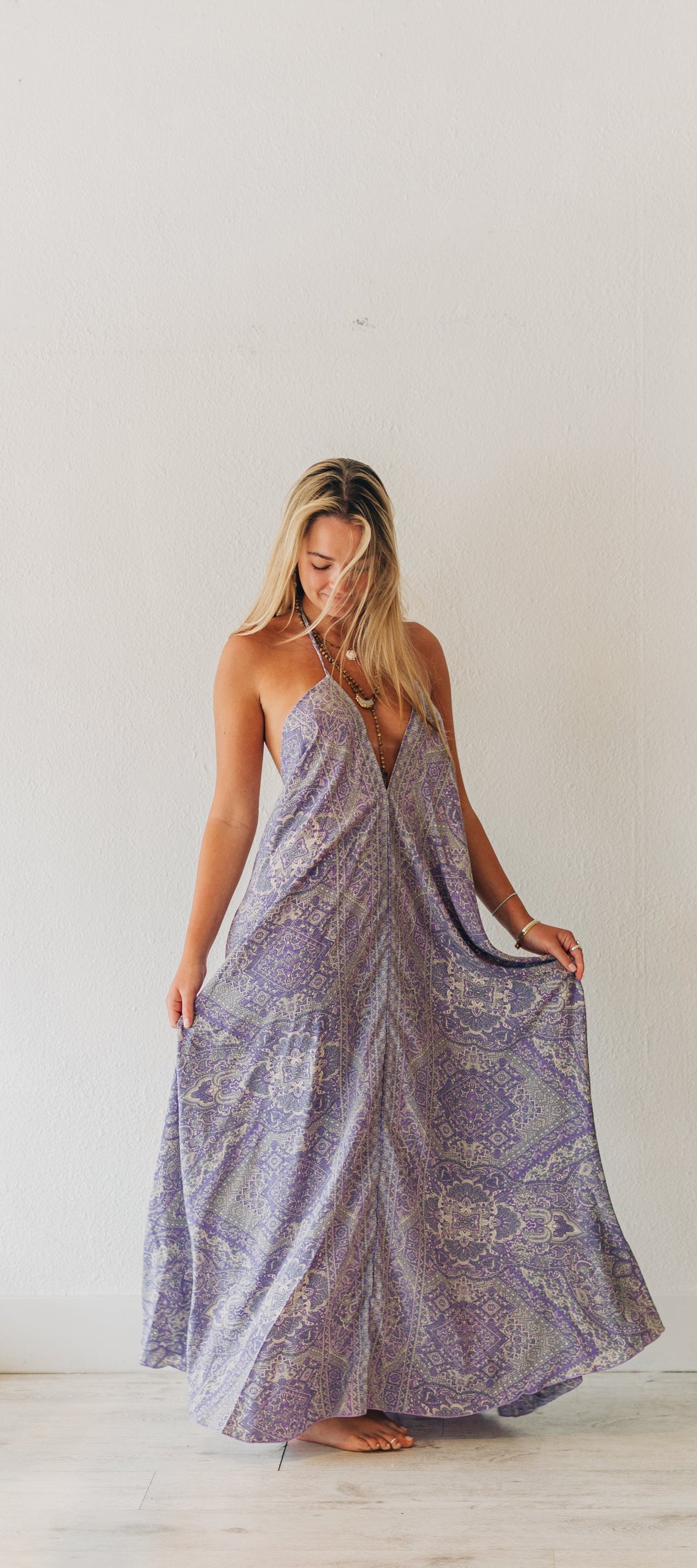 Woman wearing a long, patterned dress in a minimal indoor setting.