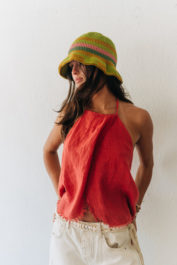 Woman wearing a red top and colorful hat against a white background