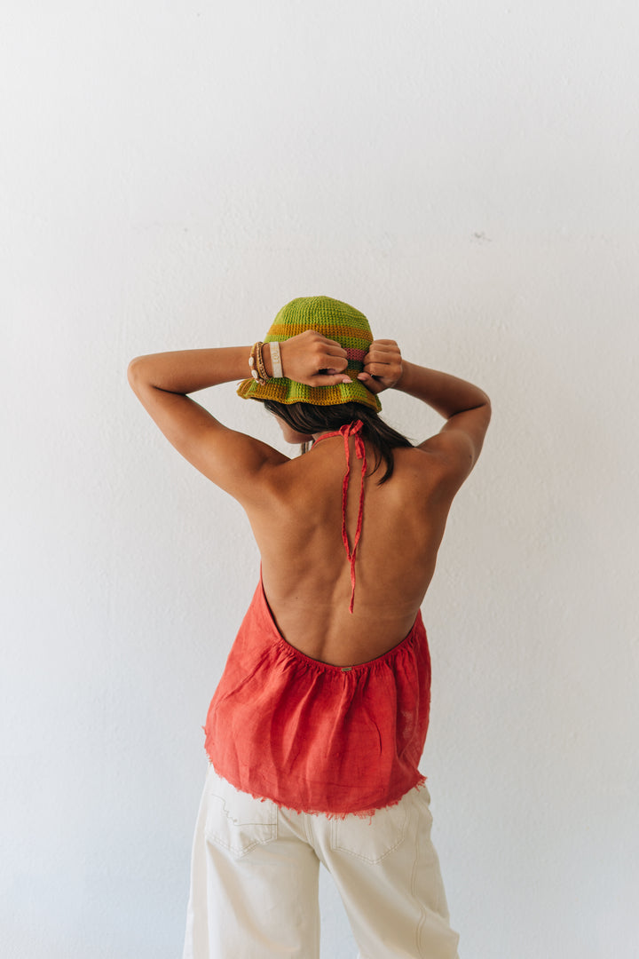 Person wearing a red top and white pants with a green hat against a white background
