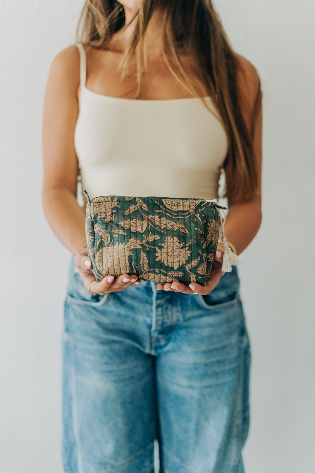 Person holding a patterned clutch against a plain background