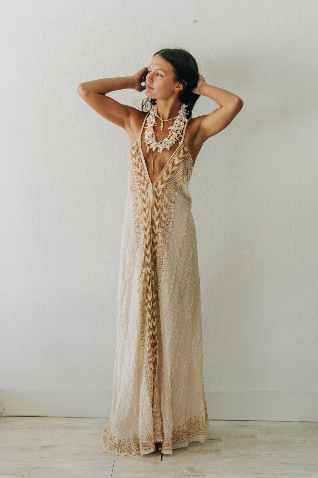 Woman wearing a long, patterned dress against a plain background