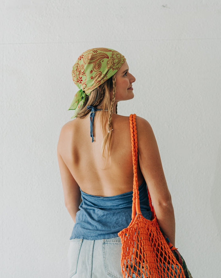 Woman with a headscarf and orange bag against a white background