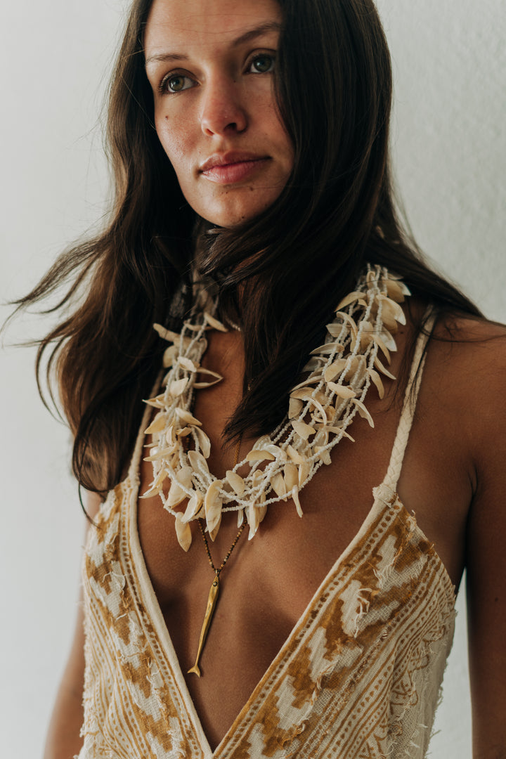 Woman wearing a decorative necklace with a plain background