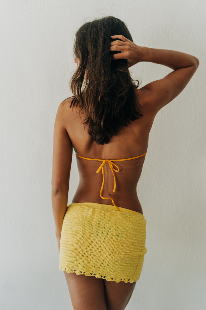 Woman wearing a yellow bikini with a white background