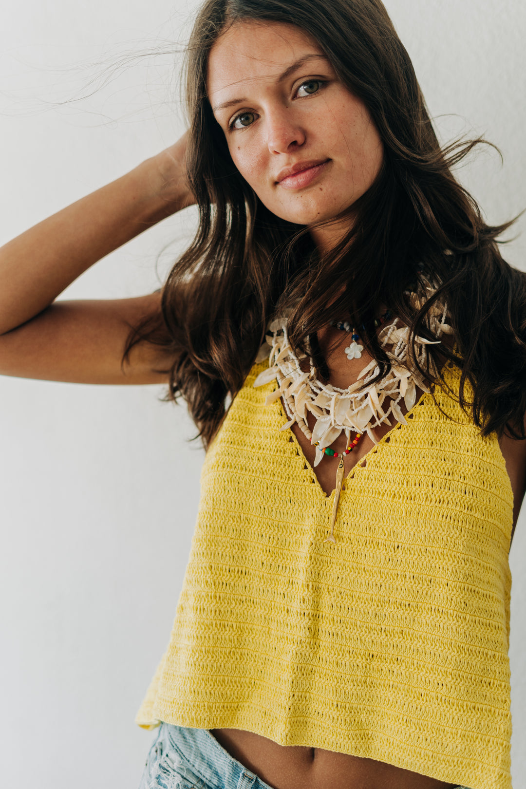 Woman wearing a yellow textured top with a white background