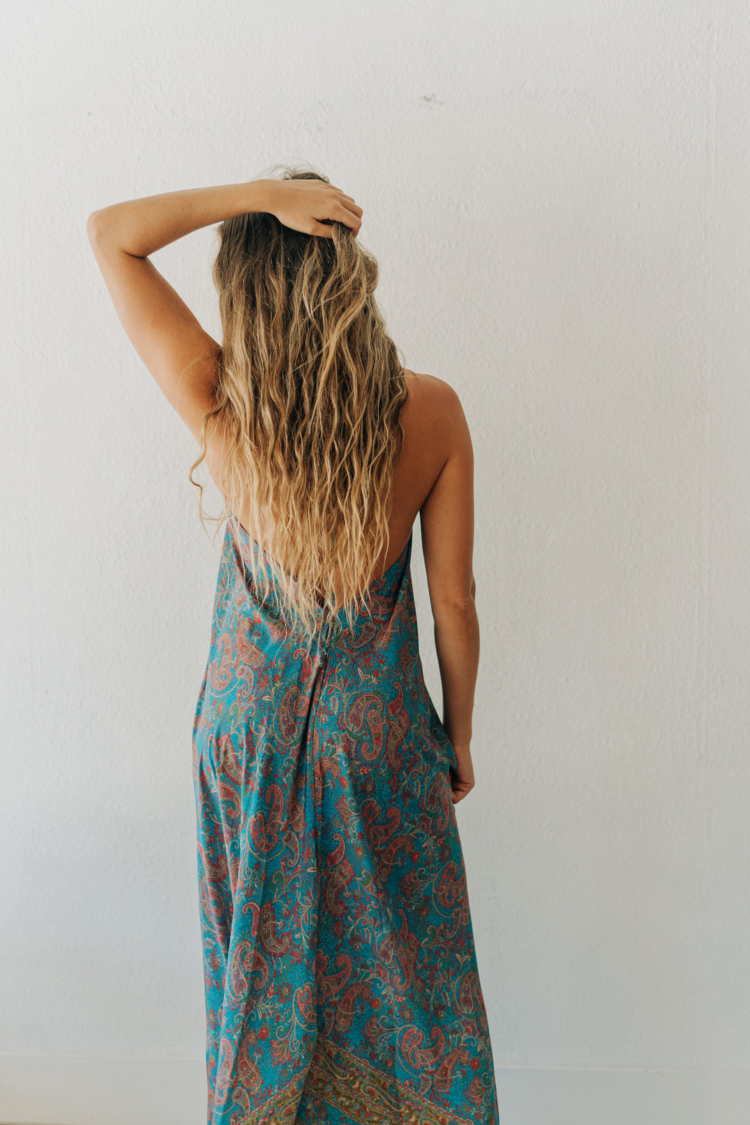 Woman wearing a blue and red patterned dress against a white wall
