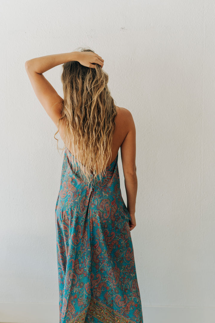Woman wearing a blue and red patterned dress against a white wall