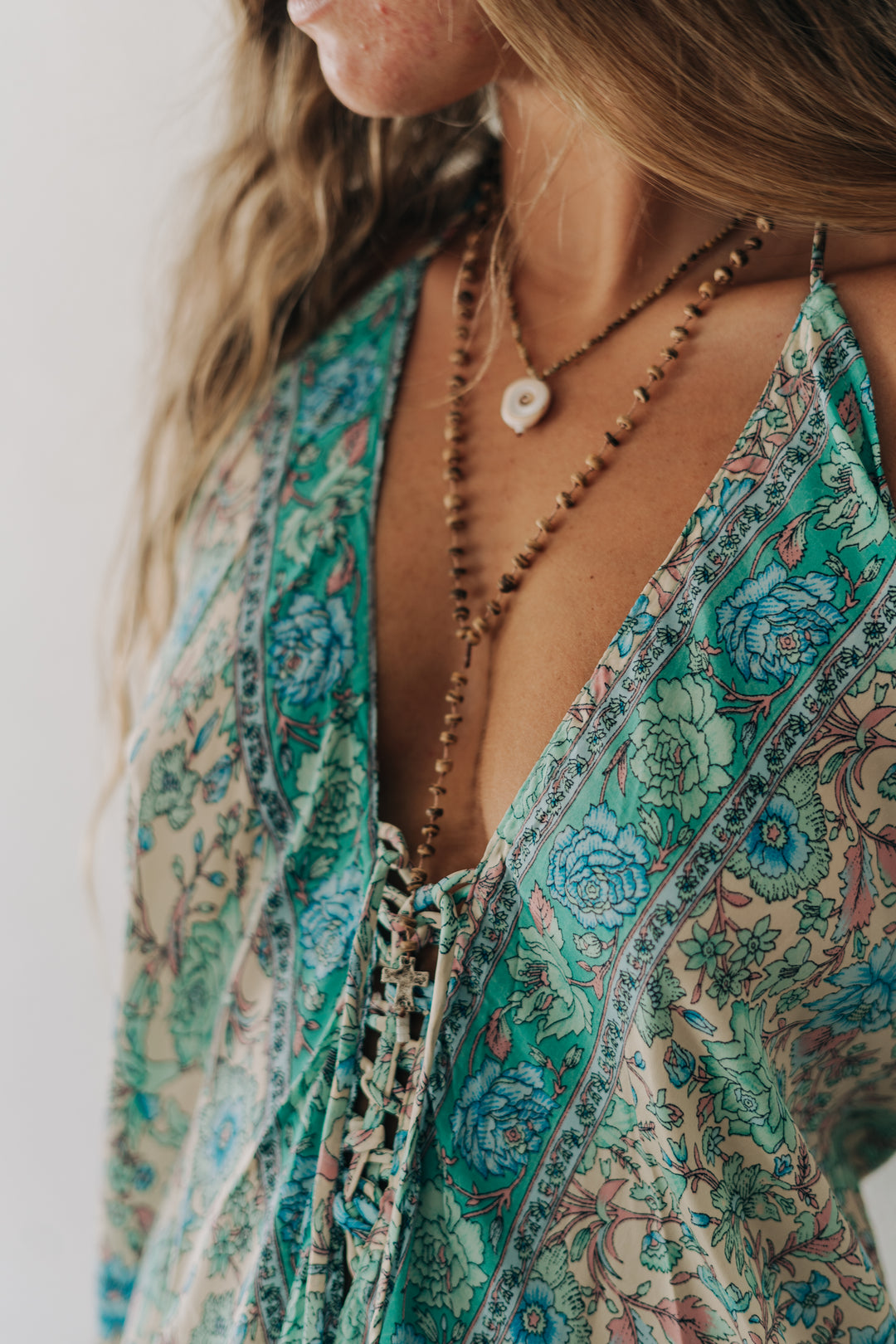 Close-up of a person wearing a patterned dress with a necklace against a neutral background