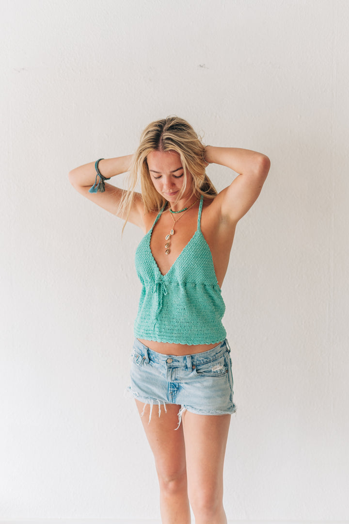 Woman wearing a green top and denim shorts against a white background