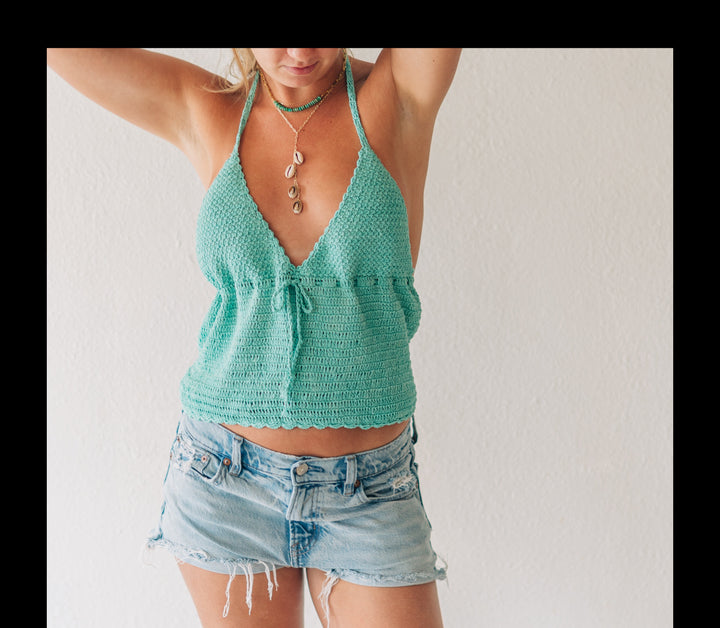 Woman wearing a green tank top and denim shorts against a white background