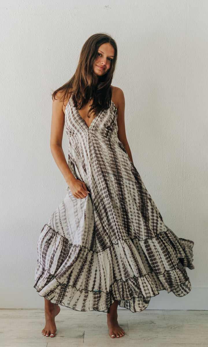 Woman wearing a long, patterned dress standing in a minimalistic room.