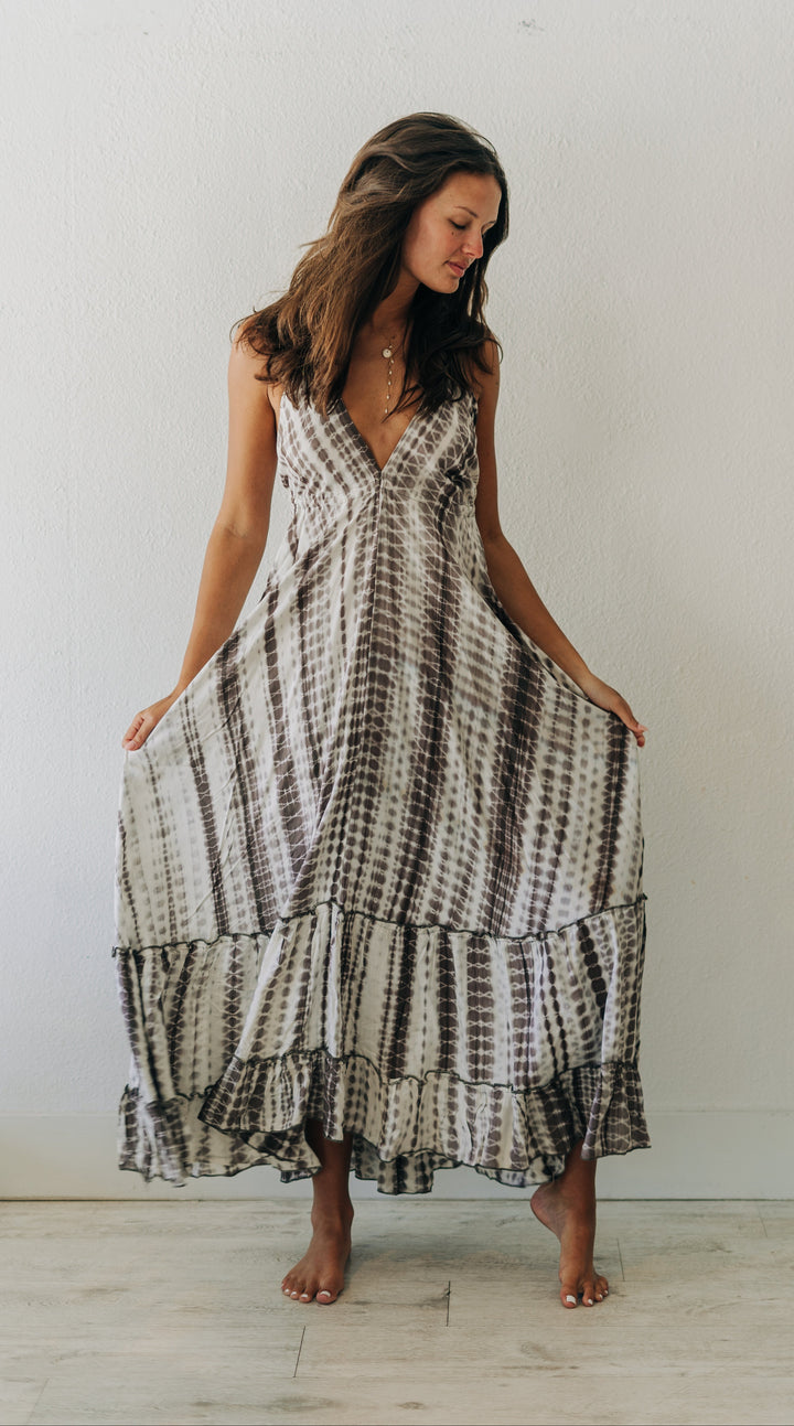 Woman wearing a black and white tie-dye dress standing against a plain white wall.