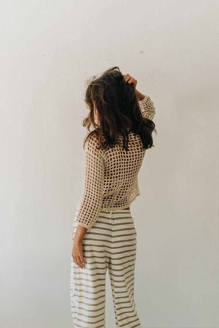 Person wearing a textured top and striped pants against a plain background