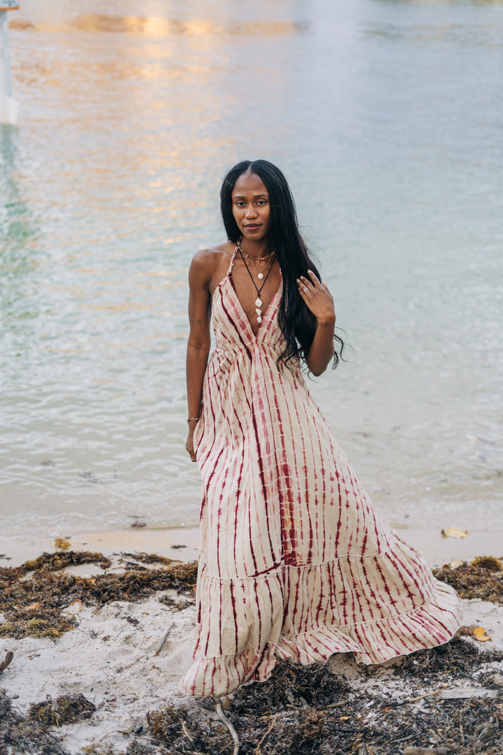 Woman in a striped dress standing on a beach with water in the background