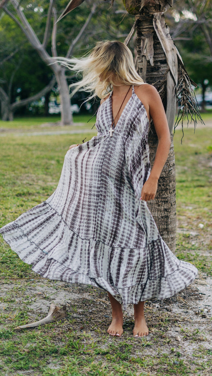 Woman in a black and white patterned dress standing under a palm tree in a natural setting
