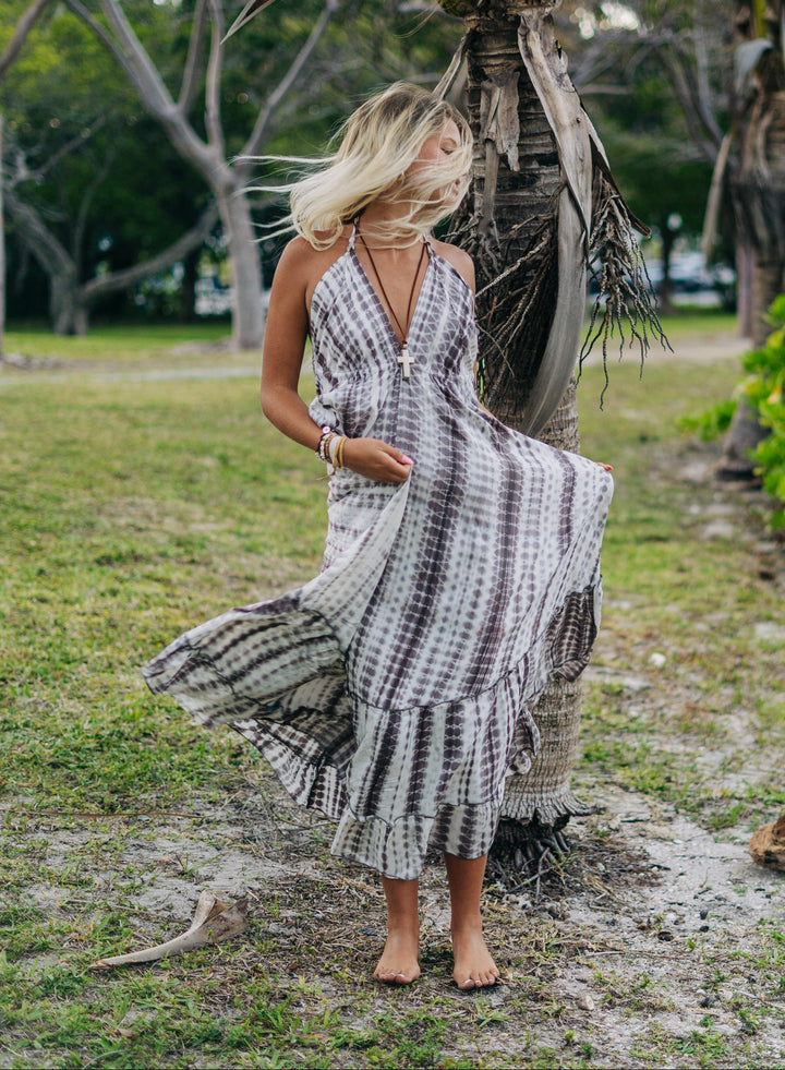 Woman in a striped dress standing under a palm tree in a park-like setting
