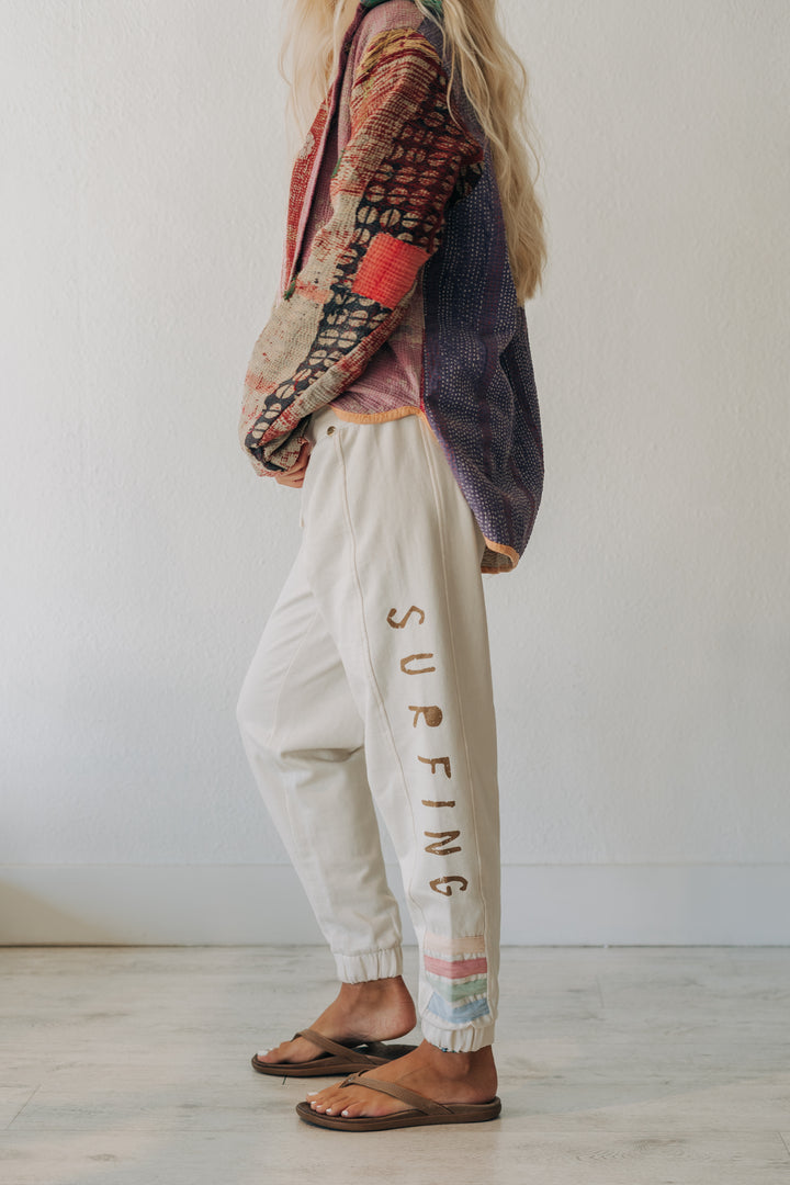 A person wearing cream-colored jogger pants with &