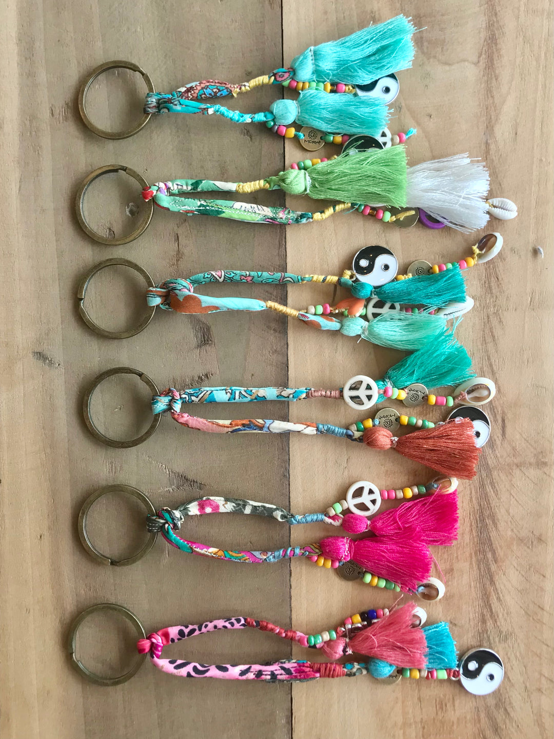A collection of handmade keychains with various colors and patterns, featuring beads, charms, and tassels.